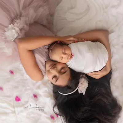 A creative and artistic portrait of an older sister lovingly cradling her newborn sibling. This overhead shot emphasizes the protective and tender connection between them from the very beginning.
