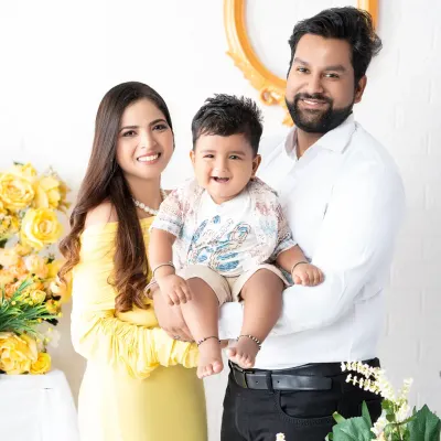 A bright and happy family portrait with a cheerful yellow theme. The family of three shares a beautiful smile, capturing a moment of pure joy in a studio decorated with yellow flowers.