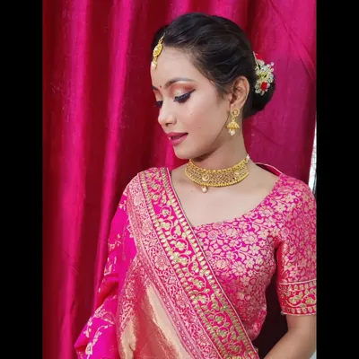 A detailed view of this festive makeup, highlighting the sharp winged eyeliner and delicate gold jewelry. The hair is neatly tied in a traditional bun with flowers, a timeless choice for any ethnic celebration.