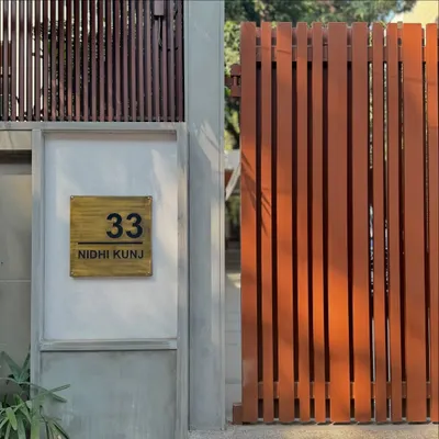 The entrance to '33 Nidhi Kunj', a soulful renovation project in New Delhi. The clean lines of the gate and the simple, elegant nameplate signal the modern and minimalist design language of the home within.