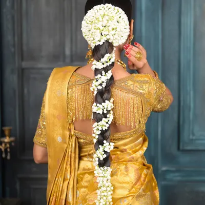 The quintessential South Indian bridal hairstyle. A long, thick braid beautifully adorned with fresh jasmine flowers (gajra), paired with a traditional bun at the top.