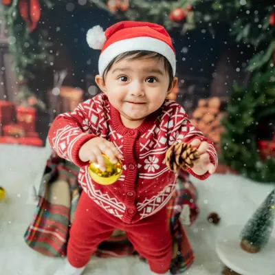 A toddler's first Christmas! This little one is having fun exploring the festive props like pinecones and shiny ornaments in my cozy, fireplace-themed holiday set.
