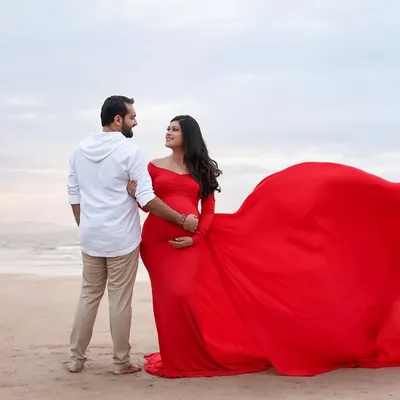 A breathtaking moment on the beach. The vibrant red of her flowing gown against the soft colors of the sea and sky creates a powerful and unforgettable image.