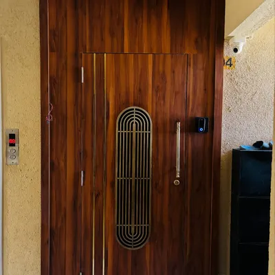 I designed this grand entrance with a solid wood safety door featuring a metal grill and brass inlays. The entire entrance area is panelled in wood to create an impressive and welcoming entryway.