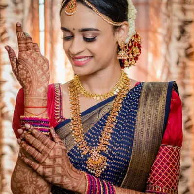 A beautiful South Indian bride admiring her bridal mehendi. The intricate design on her hands perfectly complements her traditional silk saree and gold jewelry.