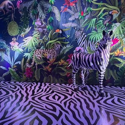 I designed this fully immersive jungle scene with a custom illustrated wall, zebra-print flooring, and a life-sized zebra prop. The moody lighting makes the space feel mysterious and wild.