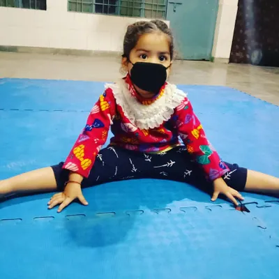 We start building a strong foundation early. This young girl is working on her flexibility, an essential part of our karate for kids program that helps prevent injuries and improves technique.