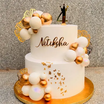 This 5-kilo two-tier cake in white and gold was a showstopper. It's decorated with clusters of white and gold spheres, gold leaf, and a custom name and age topper.