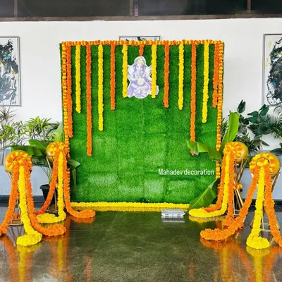 For a traditional ceremony or pooja, I created this backdrop using an artificial green grass wall. It is decorated with vertical garlands of fresh marigold flowers and a central picture of Lord Ganesha.