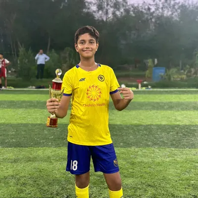 The smile of a champion. A player proudly holds his first trophy, a reward for his hard work and performance.