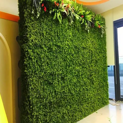 This is a dense, artificial moss-style wall with a decorative floral arrangement on top. It's a great option for creating a very lush and uniform green texture indoors.