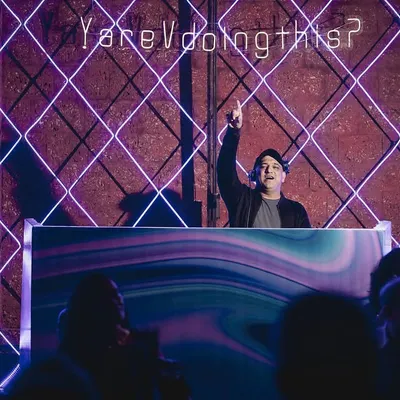 Hyping up the crowd during a 3-day wedding celebration in Mahabaleswar. The neon grid backdrop and my position above the crowd show how I command the room and keep the party going.
