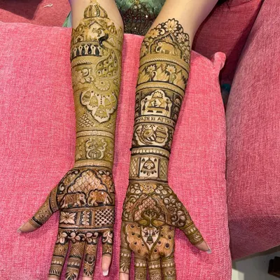 A complete bridal look with matching designs on both arms. This Rajasthani style mehndi is filled with figures, elephants, and architectural details, ensuring a grand and traditional look for the bride.