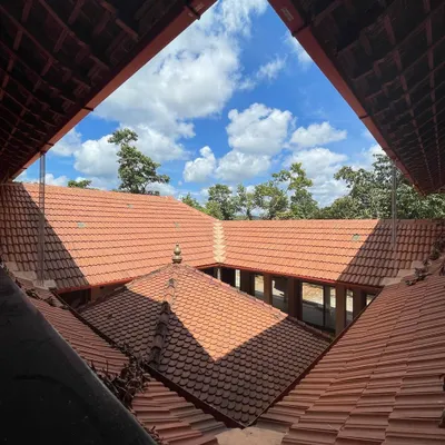 Looking up from the courtyard of 'SHANTHA-KAMALA', the Mangalore tiled roofs frame the sky, a signature element of vernacular design in the region.