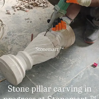 An artisan uses a precision tool for detailed carving work on a stone pillar. This piece is part of a stone birdbath fountain currently in production at our workshop.