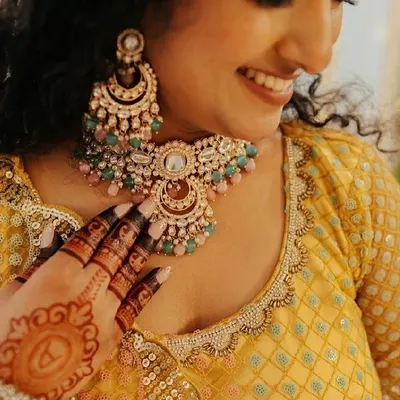 A candid shot of a beautiful client during her engagement ceremony. Her smile and the intricate mehendi on her hand perfectly capture the joy of the moment.