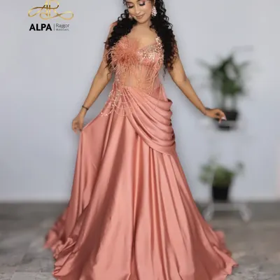 A full-length shot of a stunning peach gown perfect for a cocktail event. The makeup is glamorous with defined eyes, and the curly hairstyle adds a touch of drama.