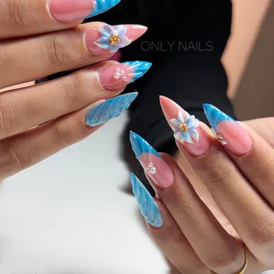An example of extreme, sculpted nail art. This set features long stiletto extensions with a blue French tip, marbled accent nails, and large, 3D sculpted flowers.