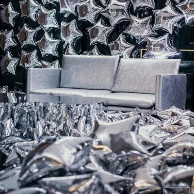 Welcome to 'The Melting Disco Ball', an after-party where we transformed a basement into a surreal disco experience. This photo booth, with its wall of silver star balloons and fringe, set the tone for a night of glam.