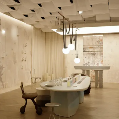 A wide view of our Mad Hatter's Tea Party installation, designed to spark curiosity. The space features a unique woven fabric ceiling, a long sculptural table for interaction, and custom globe lighting, all set against a backdrop of hand-illustrated murals that tell a story.