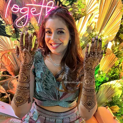 This bride's smile says it all! She looks absolutely stunning in her designer lehenga, and her custom mehendi was the perfect finishing touch for her sangeet look.