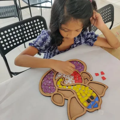 This young artist is carefully placing tiles on a Ganesha mosaic base. It's a calming and rewarding activity that helps kids with focus and fine motor skills while they create beautiful art.