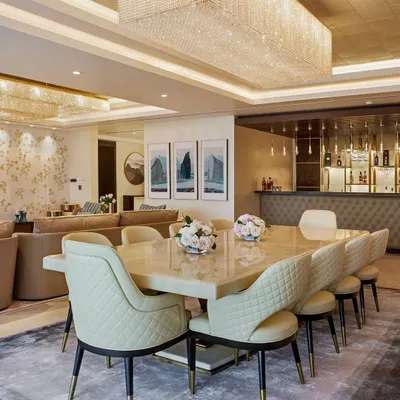 An integrated living, dining, and bar area from our Kingfisher Tower project. The design features a magnificent onyx dining table and quilted leather chairs, unified under a large crystal chandelier that creates a cohesive and luxurious atmosphere for entertaining.