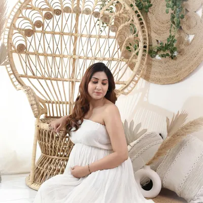 A quiet moment of reflection for this boho girl. Seated next to a peacock chair in a simple white dress, she perfectly embodies the calm and natural vibe of this style.