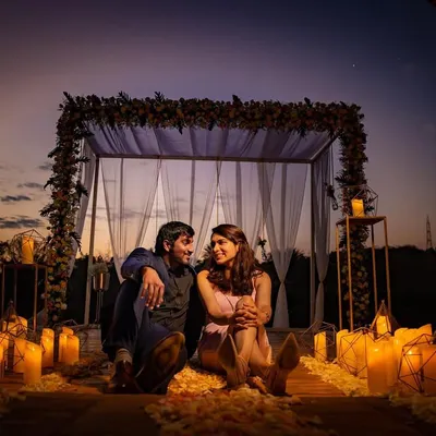 A romantic evening setup with a couple surrounded by candles and soft drapes. This is an example of a styled, intimate shoot we can create for a special occasion or proposal.