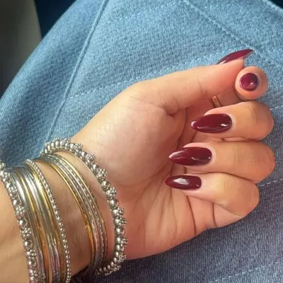 A classic and sophisticated look featuring perfectly shaped, almond gel extensions painted in a deep, glossy maroon polish.