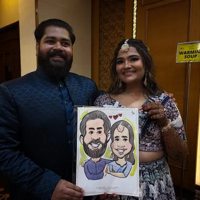 A lovely couple holding their custom portrait at what looks like a sangeet or reception. These live drawings become a memorable part of the wedding entertainment.