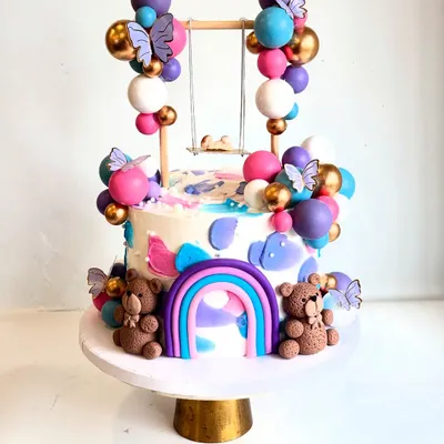 How cute is this swing baby shower cake? This unconventional design features a tiny baby on a swing, surrounded by colorful chocolate balloons, teddy bears, and a rainbow.