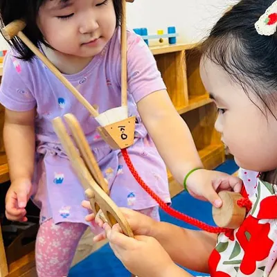 I play, I learn! Our role-play zone is a hub of activity. Here, two children are playing doctor, using a wooden stethoscope to listen to a heartbeat. This type of play helps develop empathy, communication, and an understanding of community helpers.