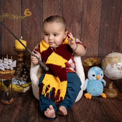 Our little wizard is casting a spell of cuteness. This Harry Potter themed setup is complete with a magic wand, a Gryffindor scarf, and vintage props to create an enchanting scene for this baby's milestone session.