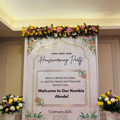 A welcoming entrance for a housewarming party. The custom "Home Sweet Home" banner, topped with a garland of fresh flowers, sets a warm and inviting tone for the new home celebration.