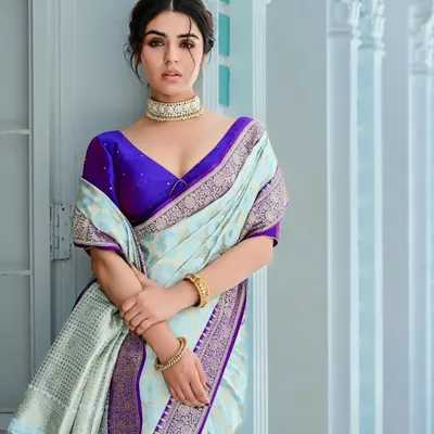 A campaign shot for saree brand Elezara. The model's elegant pose in a pastel blue and purple saree against a clean, architectural backdrop creates a look of modern sophistication.