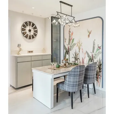 A closer look at this dining setup shows how a sleek, grey crockery unit provides essential storage while complementing the room's aesthetic. The large wall clock acts as a functional art piece, completing the sophisticated look.