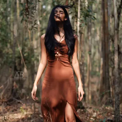A moment of pure connection with nature. The wind in her hair and the sunlight filtering through the trees create a wild and free-spirited portrait.