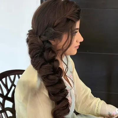 Braided with love. This thick, side-swept braid is full of texture and volume, making it a stunning choice for a Mehendi or Sangeet.