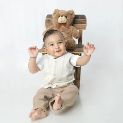 A burst of pure happiness! This little boy's joyful expression and playful pose with his teddy bear is simply infectious.