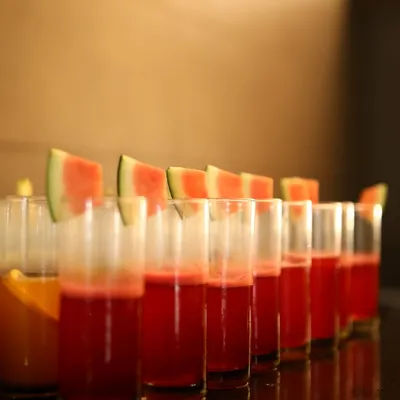 A refreshing start or a sweet interlude. These glasses of fresh watermelon juice, neatly lined up and garnished with fruit slices, are a simple yet elegant beverage option for any event.