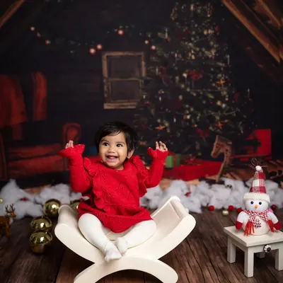 A huge, joyful smile from this baby during her Christmas mini session. The cozy cabin backdrop and festive red outfit create a perfect holiday picture.