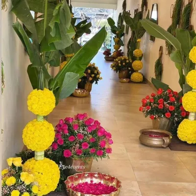 I created this blooming pathway to welcome guests to a festive celebration. The walkway is lined with arrangements of yellow marigold globes, vibrant pink roses in brass pots, and floating petals in urlis.