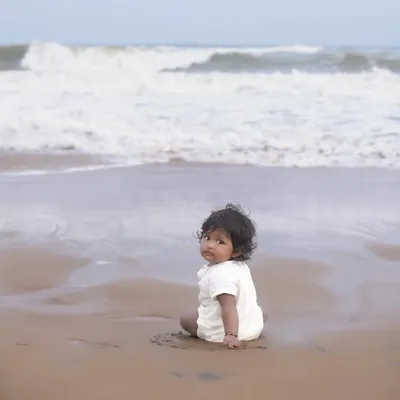 A simple, candid moment of a child enjoying the sand and waves. Our beach photoshoots aim to capture the natural beauty of the location and your child's sense of wonder.