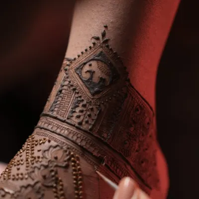 A close-up of a bridal foot mehendi in progress. This design features a small, cute elephant motif within a geometric band, a symbol of strength and good luck.