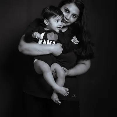 A simple and powerful black and white portrait of a mother and her child. The dark background and classic lighting create a timeless image focused on their embrace.