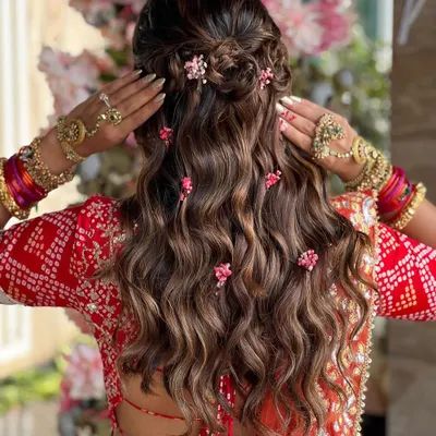 One of my favorite styles to create. This half-up look features a braided crown and soft waves, with delicate pink flowers tucked in for a romantic, bohemian vibe.