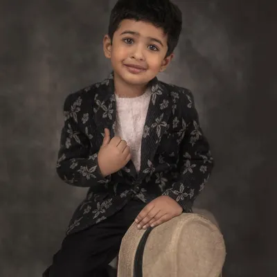 A classic, colored portrait of a young boy in a stylish floral blazer, holding a hat. The painterly backdrop and his gentle expression create a timeless piece of art.