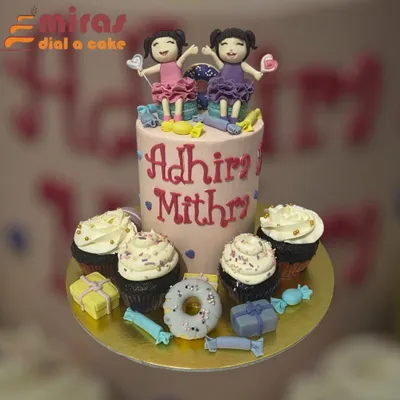 A sweet celebration for twins, this set includes a tall central cake with custom fondant figures of the birthday girls, surrounded by matching cupcakes. The theme is tied together with candy and donut decorations.