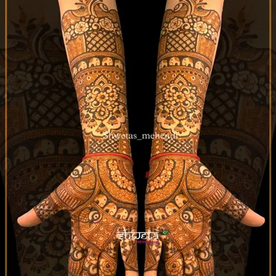 A classic elbow-length mehendi design. The patterns are fully symmetrical, featuring traditional mandala, elephant, and peacock motifs for a rich and elegant look.